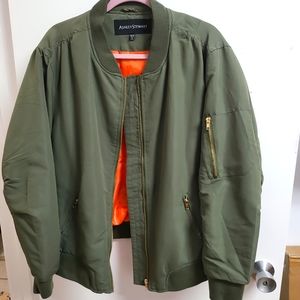 Army green bomber jacket with orange lining and gold zippers.